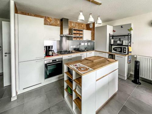 une cuisine avec des armoires blanches et un comptoir en bois dans l'établissement Appartement 3 pièces à Étel avec jardin, wifi et parking privé - FR-1-479-172, à Étel