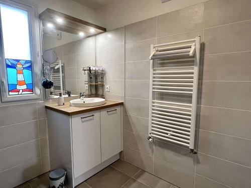 une salle de bain blanche avec un lavabo et une fenêtre dans l'établissement Appartement 3 pièces à Étel avec jardin, wifi et parking privé - FR-1-479-172, à Étel