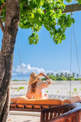 a woman sitting on a swing on the beach at WAVE SOUND by 3S Maldives in Maradhoofeydhoo