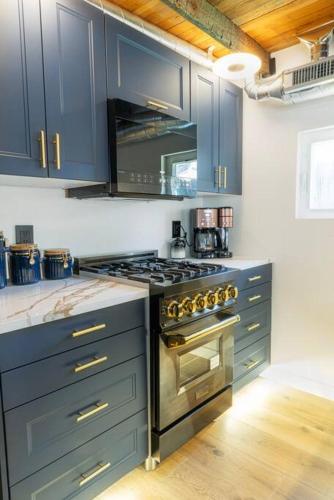 a kitchen with blue cabinets and a stove top oven at Unique Denver Tiny House Skiing, Shopping, Hiking in Englewood