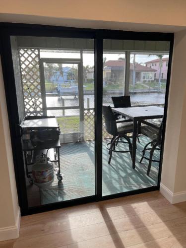 a sliding glass door with a table and a grill at WATER WATER WATER - newly renovated 3BR, 2 bath canal front home in Punta Gorda Isles in Punta Gorda
