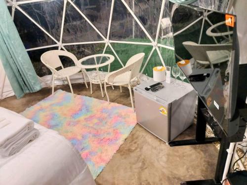 a room with a bed and chairs and a table at อินทนนท์แคมป์ปิ้ง เขื่อนสิรินธร in Sirindhorn