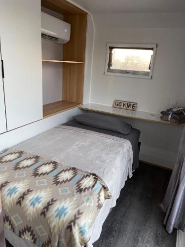 a small bedroom with a bed and a window at Black Canyon Campground Modern Sleeping Pods Tiny Homes in Black Canyon City