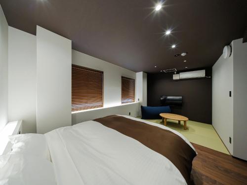 a bedroom with a white bed and a blue chair at Yunoyado Mochizuki in Myoko