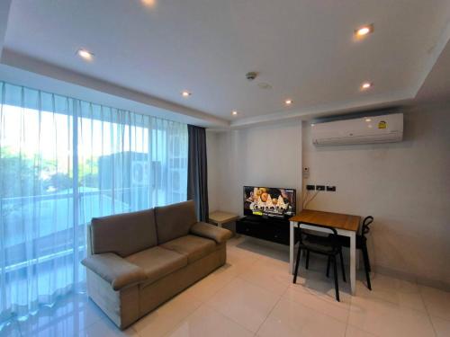 a living room with a couch and a table and a television at Serenity Wongamat Condominium 413 in North Pattaya