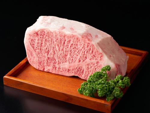 a piece of meat on a wooden plate with broccoli at Yunoyado Mochizuki in Myoko