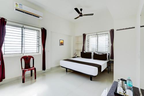 a bedroom with a bed and a chair and windows at Hotel O Elegant Residency Vandalur Zoo in Chennai