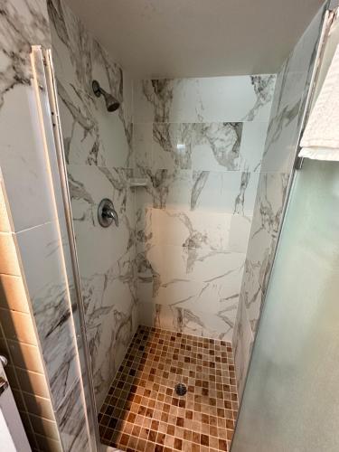 a bathroom with a shower with a tiled floor at Ramblin Rose Motel in Kingman