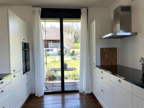 a kitchen with white cabinets and a large glass door at Cloud Garden Maisonette in Spiez