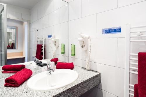 a white bathroom with a sink and red towels at Hotel Deutsches Haus in Bonn