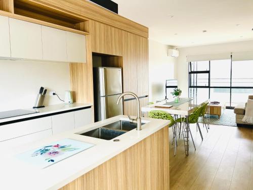 a kitchen with a sink and a living room at Lake Quarter Apartment in Auckland