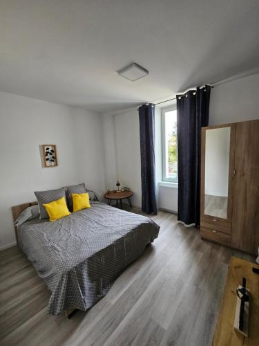 a bedroom with a bed with yellow pillows and a window at La famille 1 in Angoulême