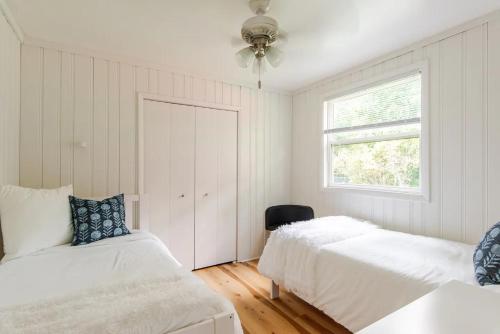 a white bedroom with two beds and a window at Lakeside Retreat - Cozy Cottage with Firepit in Hartland