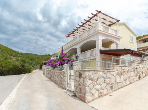 ein Gebäude auf einer Steinmauer mit Blumen darauf in der Unterkunft Modern Villa Near the Sea in Blato