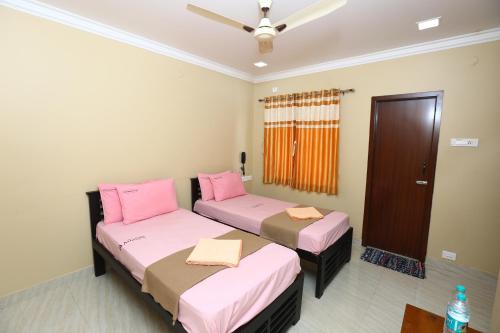 two beds in a room with pink and brown at Ramana's Home Stay-Near Railway Station and Bus Stand in Thanjāvūr