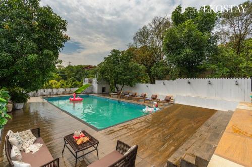a swimming pool in a backyard with chairs and a swimming pool at EKOSTAY - Amanta Hills 7BHK in Karjat