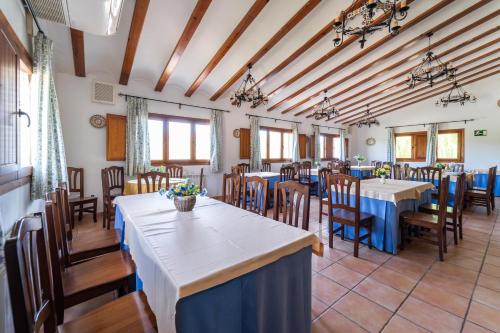 ein Esszimmer mit Tischen, Stühlen und Fenstern in der Unterkunft El Moral Centro de Turismo Rural in Valdecañas