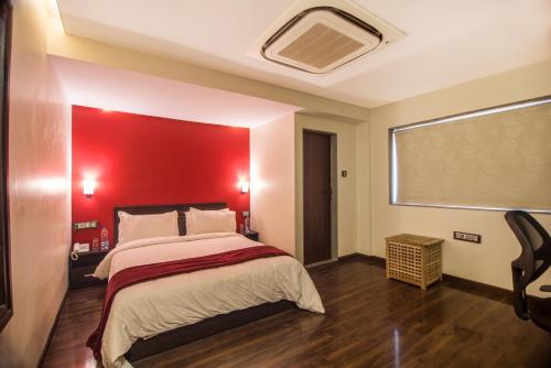 a bedroom with a large bed with a red wall at The V Sadan in Mumbai