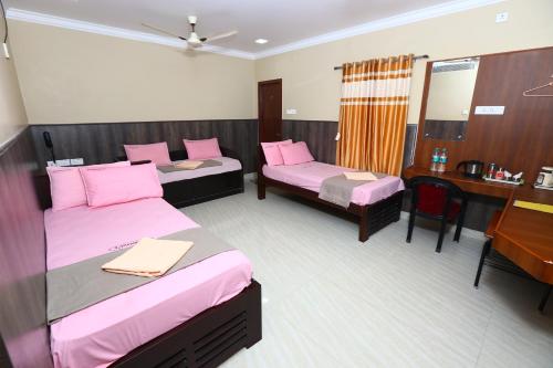 a hotel room with two beds and a desk at Ramana's Home Stay-Near Railway Station and Bus Stand in Thanjāvūr
