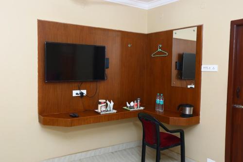 a room with a television on a wall with a chair at Ramana's Home Stay-Near Railway Station and Bus Stand in Thanjāvūr