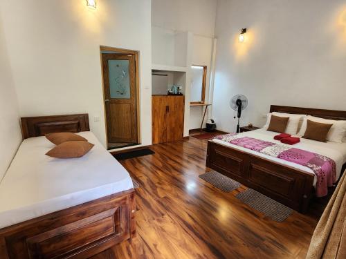 two beds in a room with wooden floors at Poomaz Peace Palace in Ella