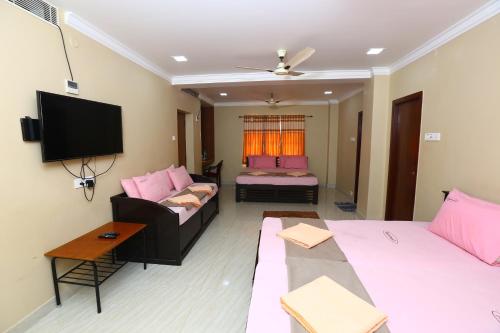 a living room with two beds and a flat screen tv at Ramana's Home Stay-Near Railway Station and Bus Stand in Thanjāvūr
