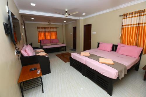 two beds in a room with pink pillows at Ramana's Home Stay-Near Railway Station and Bus Stand in Thanjāvūr