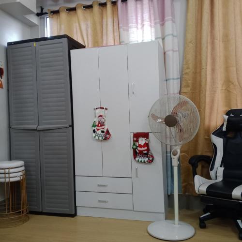 a white cabinet next to a fan and a chair at Sweet Stay at Manila in Manila