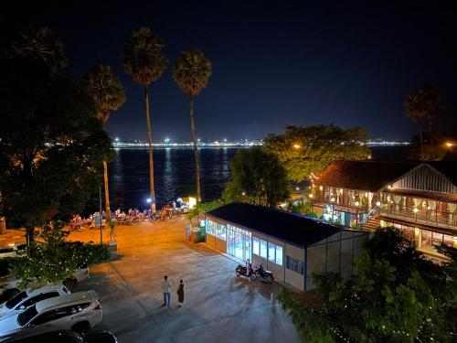 a building with palm trees in front of the water at night at Chandala Hotel in Thakhek
