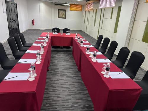 a long table in a room with red tables and chairs at Hotel Seri Malaysia Pulau Pinang in Bayan Lepas