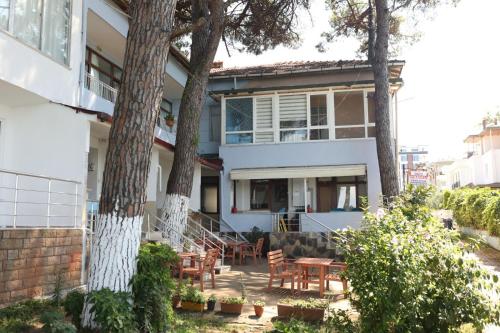 a white house with trees and tables and chairs at Sahil Evim Pansiyon in Unye