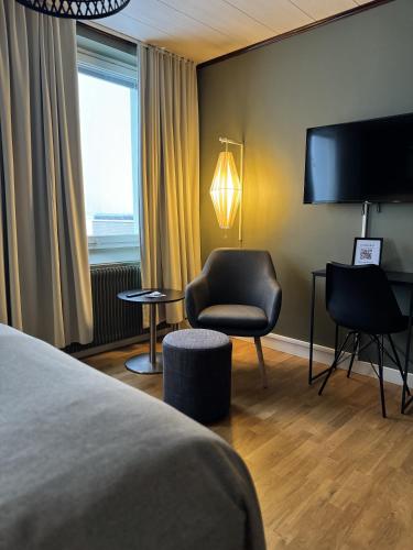 a hotel room with a bed and a chair and a television at Strand City Hotel in Örnsköldsvik