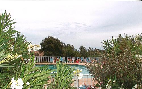 une piscine avec des personnes assises sur une clôture dans l'établissement Au jardin du golfe, au Plan-de-la-Tour