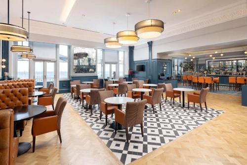 a restaurant with tables and chairs and windows at DoubleTree By Hilton Brighton Metropole in Brighton & Hove