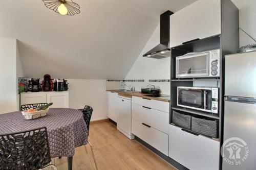 a small kitchen with a table and a refrigerator at Des faudours in Plérin