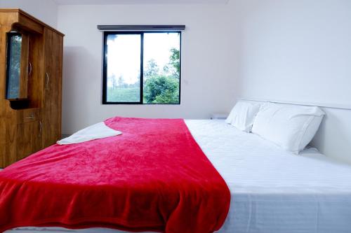 a bedroom with a bed with a red blanket on it at Green Garden Jasmin Cottage in Vayittiri