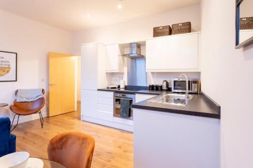 a kitchen with white cabinets and a table and a chair at Modern 2- Bedroom Apartment in Central Redhill! in Redhill