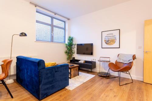 a living room with a blue couch and a tv at Modern 2- Bedroom Apartment in Central Redhill! in Redhill