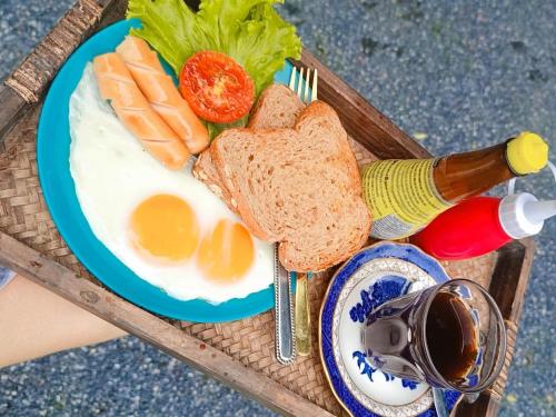 a plate of eggs and bread and a bottle of beer at Lanta bluewave Bungkalow in Phra Ae beach