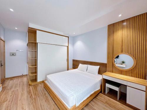 a bedroom with a bed and a desk and a mirror at Bay Homestay in Cam Lâm