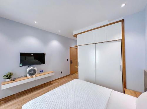 a bedroom with a bed and a tv on the wall at Bay Homestay in Cam Lâm