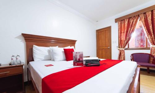 a bedroom with a large bed with a red blanket at RedDoorz Plus @ Starhomes Olivianville in Tarlac
