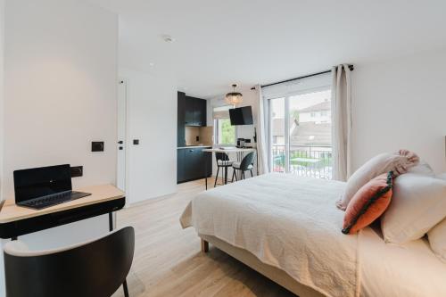 a bedroom with a bed and a desk with a laptop at Appart Hotel Neostelia in Annecy