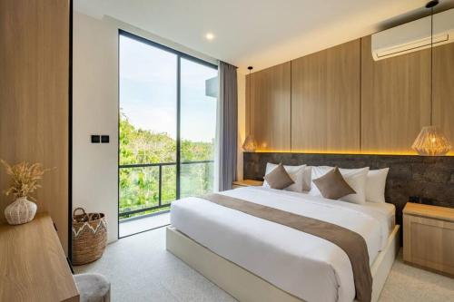 ein Schlafzimmer mit einem großen Bett und einem großen Fenster in der Unterkunft Private Villa Ayra 8C by OriVista 10mins to Melasti Beach in Uluwatu