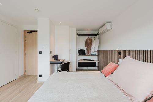 a bedroom with a white bed and a desk at Appart Hotel Neostelia in Annecy
