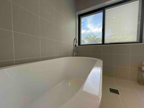 a large white tub in a bathroom with a window at HOKULANI elua in Chōjamachi