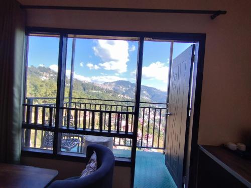a room with a balcony with a view of a mountain at Hotel Aachman Regency with Rooftop Terrace in Shimla
