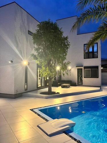 a house with a swimming pool in front of a building at HOKULANI elua in Chōjamachi