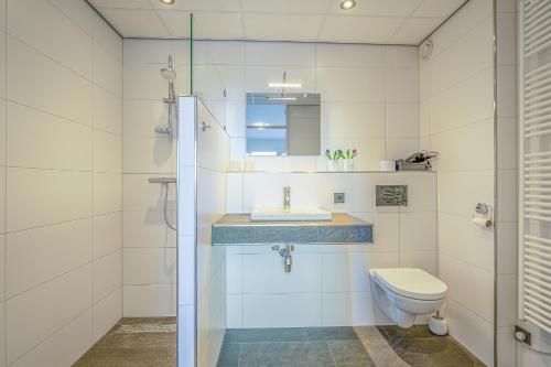a white bathroom with a sink and a toilet at Appartementencomplex Juliana 78 in De Koog