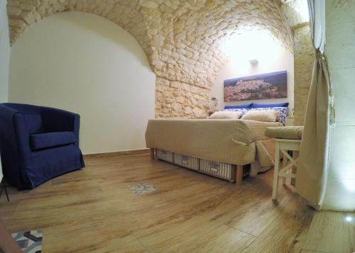 a room with a bed and a chair and a stone wall at Al Borgo dell'Arte Suite in Scicli